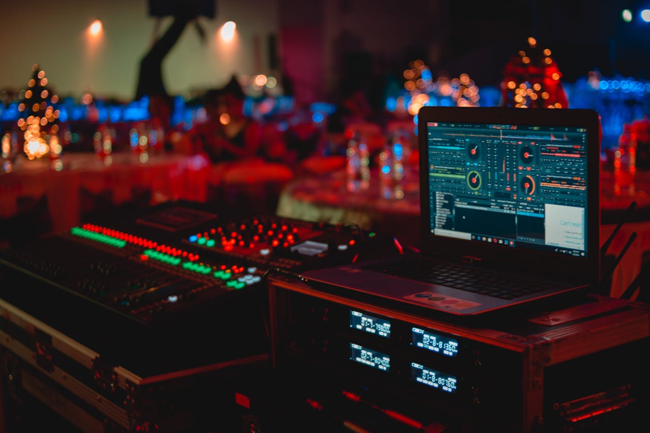mobile-01 Vivid DJ setup with laptop and sound mixer at a lively indoor event.